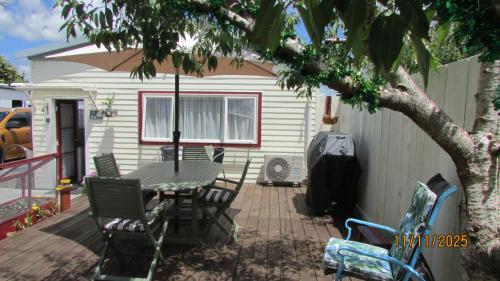 a patio with a table and chairs and a house at Cozy Haven - Waihi in Waihi