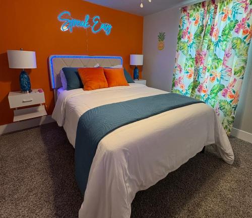 ein Schlafzimmer mit einem großen Bett mit einer orangefarbenen Wand in der Unterkunft Casa Amor Texas A Vibrant Villa near BS&W with King Bed in Temple
