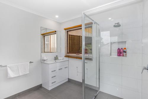 a white bathroom with a shower and a sink at Bendigo Signature Accommodation on Vine in Bendigo