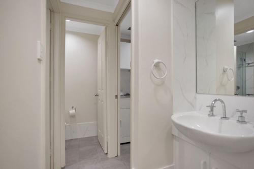 Nautilus 2 - Ground Floor Unit في هاوكس نيست: حمام أبيض مع حوض ومرآة