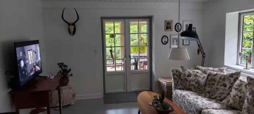 a living room with a couch and a tv at Hyggelig Hus Nær Arrild Ferieby in Arrild