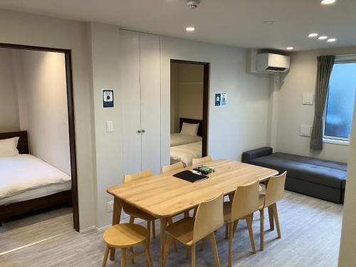 Una habitación con una mesa y sillas y un dormitorio. en PRISM Inn Tateishi, en Tokio