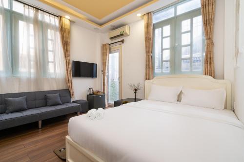a bedroom with a large white bed and a couch at Rocky Hotel Ho Chi Minh in Ho Chi Minh City
