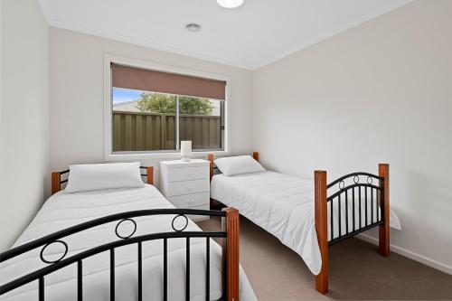 two beds in a room with a window at Time to Relax in Portarlington