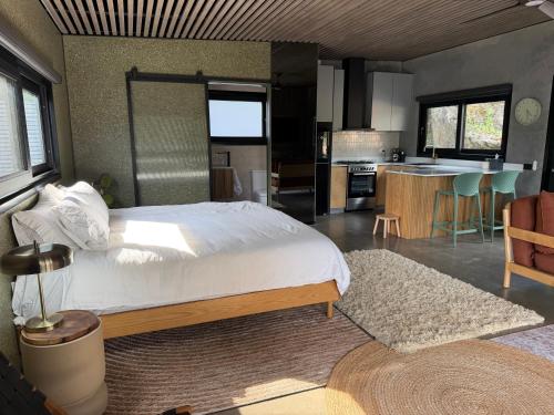 a bedroom with a large bed and a kitchen at Chapel Cove Retreat - Private Tiny House with Boat Ramp in Sackville Reach