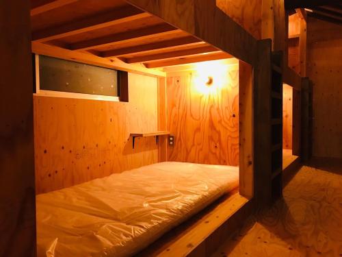 Konanコワーキングスペース kuzume Base ゲストハウス TOMARUKU的一间木墙内有一张床的房间