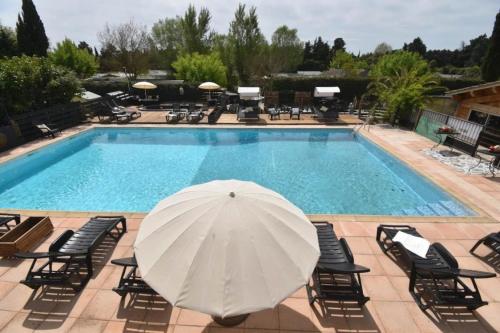 a pool with a white umbrella and chairs at ZEcamping 4 étoiles pet friendly piscine et pétanque au cœur des Alpilles in Noves