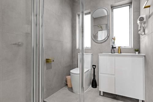 a bathroom with a toilet and a sink and a mirror at Inviting Double Room with Sunlit Comfort - Matraville - Shared Bathroom and Kitchen in Sydney