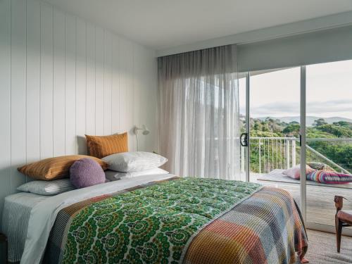 een slaapkamer met een bed en een groot raam bij Frankie Beach House in Bicheno