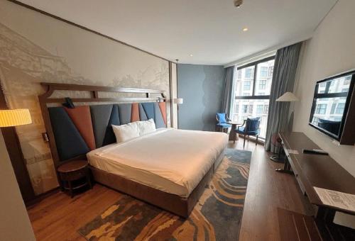 a hotel room with a bed and a television at Apec Mandala Cham Bay Condotel Mui Ne in Mui Ne