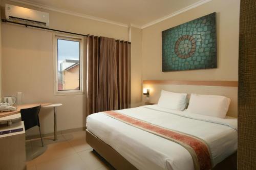 a hotel room with a bed and a desk and a window at Laxston Hotel in Yogyakarta