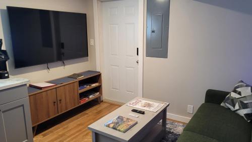 a living room with a tv and a couch and a table at The Suite Treat in Whitehorse