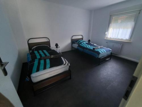 twee bedden in een kleine kamer met een raam bij Mego Unterkünfte in Bönen