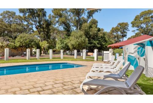 a group of lounge chairs next to a swimming pool at Discovery Parks - Woodman Point in Coogee
