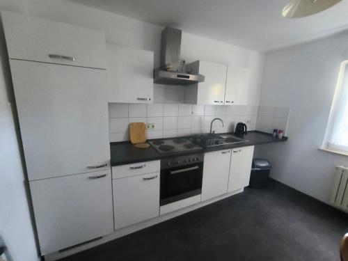 een witte keuken met een spoelbak en een fornuis bij Mego Unterkünfte in Bönen