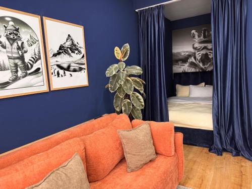 een woonkamer met een oranje bank en een slaapkamer bij Ski Zoo Apartments, new gudauri in Kʼumlistsʼikhe