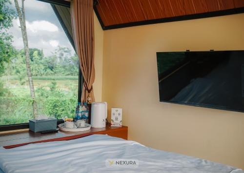 Un dormitorio con una cama y una ventana grande en The Kotenang, en Wonosobo