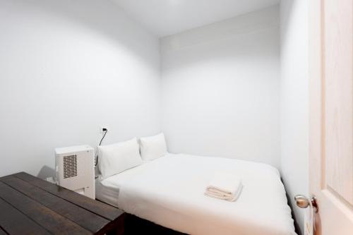 a bedroom with a white bed and a desk with a radiator at xx Mitr Inn Khaosan มิตร อินน์ ตรอกข้าวสาร in Bangkok