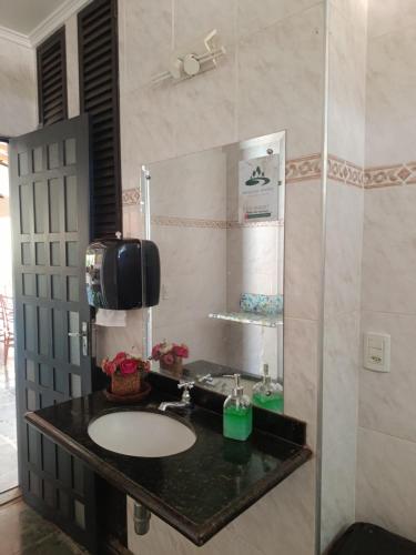 a bathroom with a sink and a mirror at Parque das árvores hospedagem e eventos in Barretos