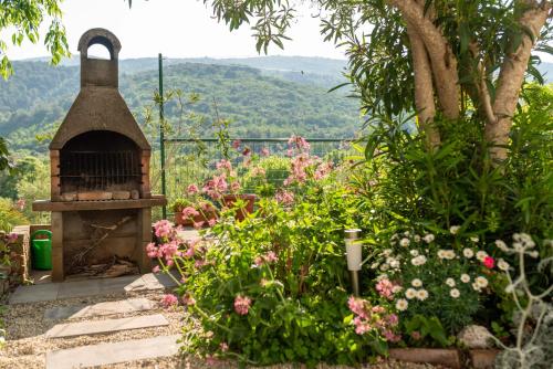 Un jardín con un horno de ladrillo en medio de flores. en Haus Gaia, en Rabac