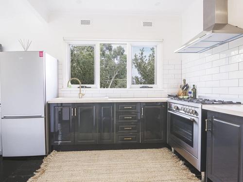 a kitchen with black cabinets and a white refrigerator at Healesville Gardener's Cottage in Healesville