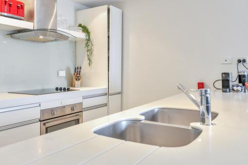a white kitchen with a sink and a counter at Luxury in Litchfield Street - Heart of the CBD in Darwin