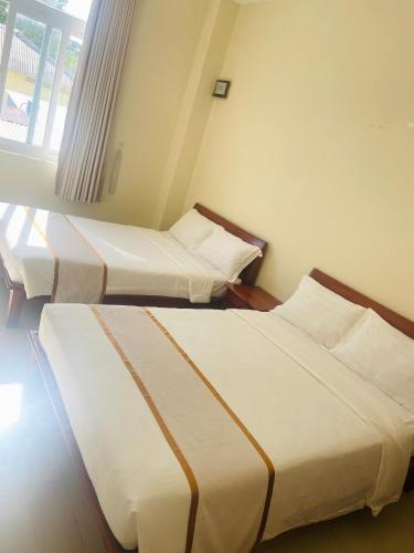 two beds in a hotel room with a window at Thien Phu Nghia 2 - Hotel Phu Quoc in Phú Quốc