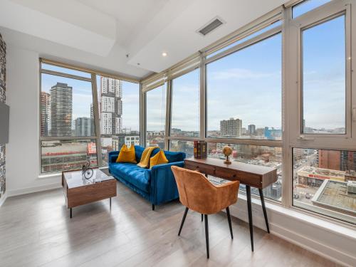 a living room with a blue couch and large windows at VOGUE Suites Toronto Downtown - Entertainment District in Toronto