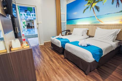 Una habitación de hotel con dos camas y un televisor. en Sunrise Hotel Malang, en Rampal