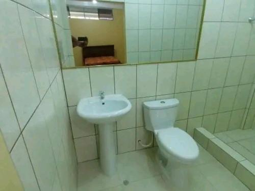 een badkamer met een wastafel, een toilet en een spiegel bij Emerald forest apartment in Iquitos