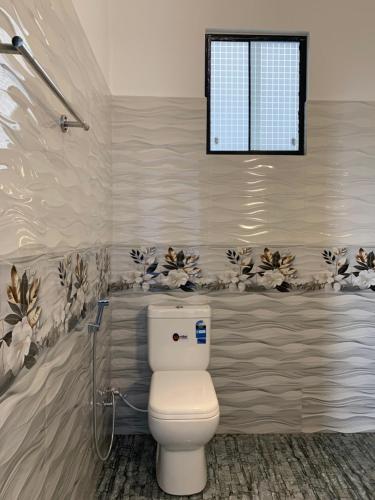 a bathroom with a toilet and a window at The Rosemary House in Weligama