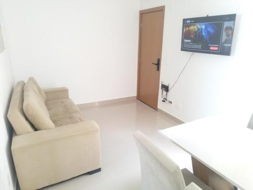 a living room with a couch and a tv on a wall at FLAT ACONCHEGANTE poucos min da praia in Maceió