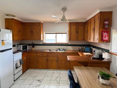 eine Küche mit Holzschränken und einem weißen Kühlschrank in der Unterkunft Park, Outdoor Gym, Sports Oval, 3 Queen Room House in Broken Hill