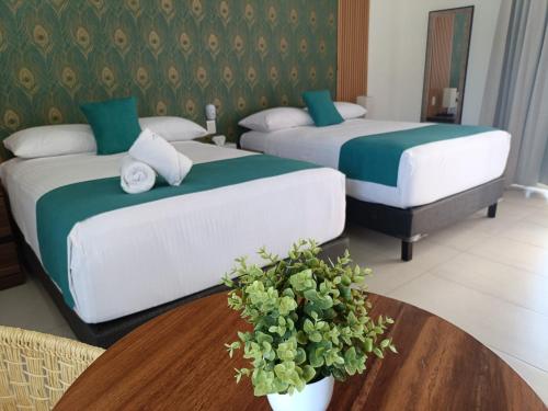 two beds in a hotel room with a table at Punta Colibrí in Brisas de Zicatela