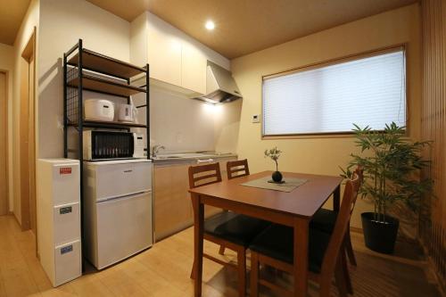 a small kitchen with a table and a refrigerator at Kamon Inn Uji 2-D in Uji