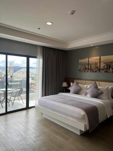 a bedroom with a large bed and a large window at Doña Manor Boutique Hotel in Olongapo