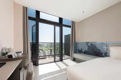 een slaapkamer met een bed en een balkon met een tafel bij Atour Light Hotel Cixi Sports Center Xinhefang in Hushan