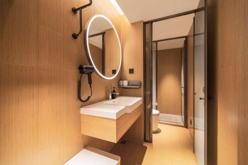 ein Badezimmer mit einem weißen Waschbecken und einem Spiegel in der Unterkunft All Seasons Hotel Guangzhou Wuyangcun Metro Station in Guangzhou