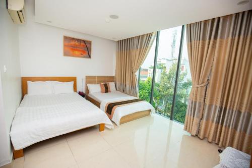 a bedroom with two beds and a large window at Ruby Star Hotel Apartment in Vung Tau