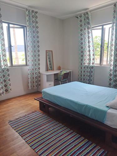 a bedroom with a bed and two windows and a rug at Chez Mya in Cascavelle