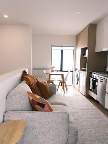 een woonkamer met een grijze bank en een tafel bij The Urban Nest in Wellington