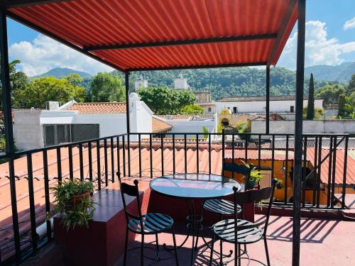 Un patio con una mesa y sillas en un balcón. en Casa Altavista, en Antigua Guatemala