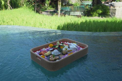 Una canasta llena de juguetes en el agua. en Queen at Gunung Sari, en Ubud