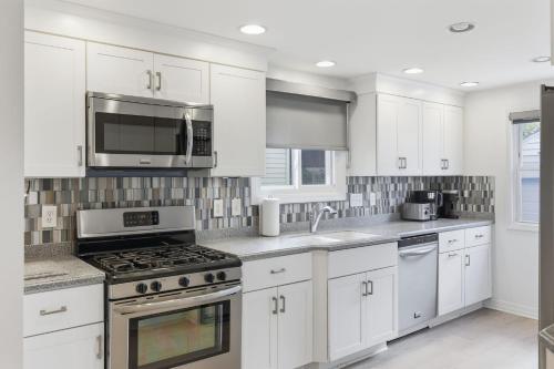 a kitchen with white cabinets and a stove and microwave at Snyder Sanctuary Retreat home in Amherst