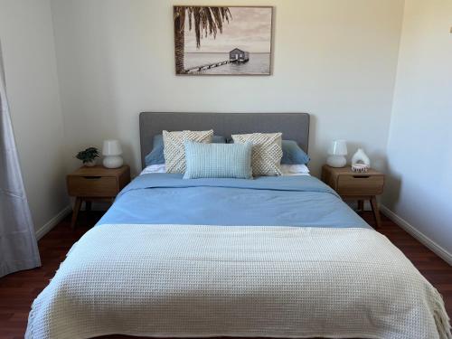 a bedroom with a bed with a blue and white comforter at The Little Beach Retreat - Relaxing family sized home one street from the sea! in Port Willunga