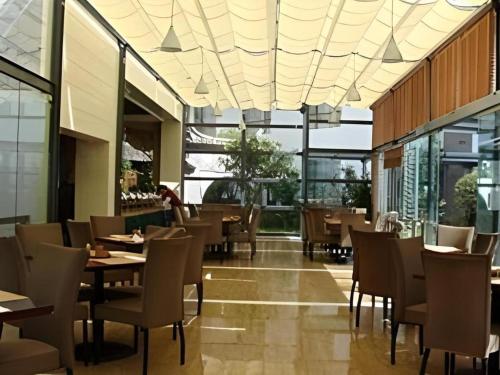 a restaurant with tables and chairs and windows at Lijiang Conifer Lishui Yangguang Hotel in Lijiang