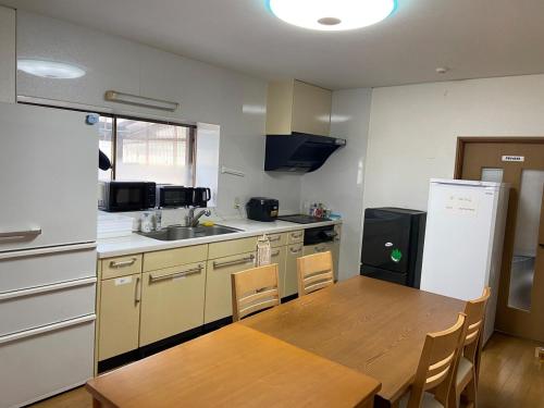 a kitchen with a wooden table and a refrigerator at 湖を望む一軒家 in Wakasa