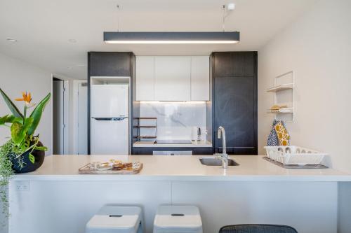 a kitchen with a sink and a counter with stools at Executive Two bedroom & two bathrooms in Melbourne