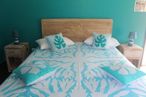 1 cama con edredón y almohadas azules y blancos en Vai'Ute'Ute Lodge, Raiatea, en Tevaitoa