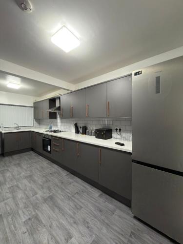 a large kitchen with gray cabinets and white counter tops at Kings Lodge in Manchester